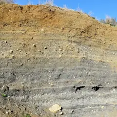 Capas de tierra y grava expuestas en un corte, mostrando la geología del volca de la Crosa.