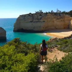 Una mujer admira las impresionantes calas del Algarve, con sus acantilados dorados y aguas turquesas.