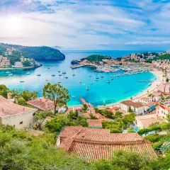 Bahía turquesa con barcos y casas en laderas verdes, un paraíso que evoca **islas secretas** y tranquilidad.
