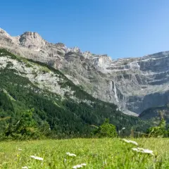 Majestuoso circo de Gavarnie con cascada y prado verde.