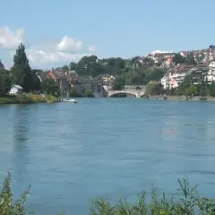 Un río azul fluye hacia una ciudad con iglesias y casas en la ladera, parte de la ruta EuroVelo 15.