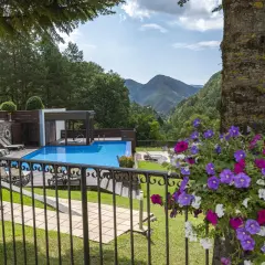 Un hotel de montaña con piscina azul, rodeado de vegetación. La coma i la pedra, un lugar de ensueño.