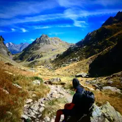 Senderista contempla la inmensidad de los montes Pirineos bajo un cielo azul intenso.