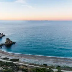 Vista aérea de una cala rocosa y una playa de guijarros en las playas de Málaga al amanecer.