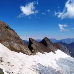 Paisaje de alta montaña con nieve y rocas en el pico Viñamala. El cielo azul intenso contrasta con las cumbres nevadas y las formaciones rocosas.