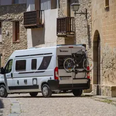 Furgoneta blanca con portabicicletas trasero, mostrando cómo llevar la bici dentro de la furgoneta para aventuras.