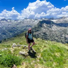 Senderista disfruta de las impresionantes vistas de las rutas del Valle de Arán, con picos nevados y un cielo azul con nubes.