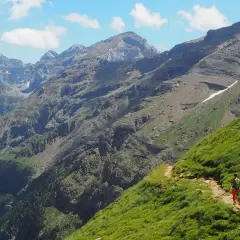 Senderista en un camino escarpado con vistas a las majestuosas montañas de Ordesa Monte Perdido.