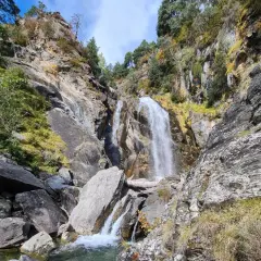 Cascada imponente en la ruta Rupit, rodeada de rocas y vegetación otoñal. El agua cae con fuerza sobre las piedras, creando un paisaje natural espectacular.