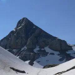 Majestuosa cumbre rocosa en el **valle de Belagua**, con nieve en sus laderas y un cielo azul intenso.