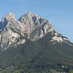 Majestuoso Pedraforca, cumbre rocosa coronada por pinos. Una ruta de senderismo desafiante espera.