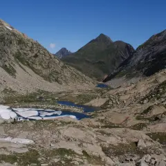 Paisaje de montaña con lagos glaciares y restos de nieve. El pico Mulleres se alza majestuoso en el horizonte.