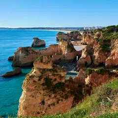 Acantilados dorados y mar turquesa en las **playas de Portugal**. Un paisaje idílico con formaciones rocosas y vegetación exuberante.
