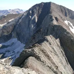 Cresta rocosa y escarpada, con restos de nieve, que se asemeja a un pico espadas en la inmensidad de las montañas.