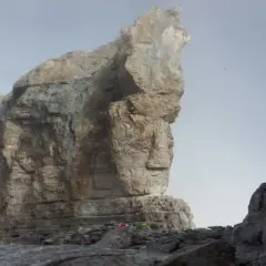 Impresionante vista de la brecha de Rolando, con imponentes formaciones rocosas y un cielo brumoso. Pequeños puntos de color sugieren la presencia de excursionistas.