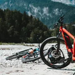 Aventura en Croacia en bicicleta, con bicicletas de montaña listas junto a un río pedregoso y un bosque frondoso.