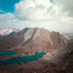 Paisaje montañoso con lagos turquesa, como si fueran los picos del infierno. Nubes blancas y cielo azul.