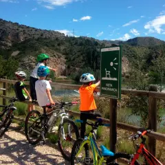 Niños en bicicleta disfrutan de la **vía verde Val de Zafán**, señalizada con un mirador panorámico.