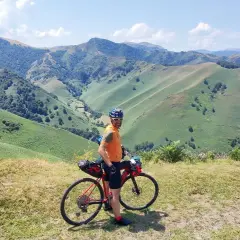 Ciclista con su bicicleta de gravel en un paisaje montañoso verde, disfrutando de la ruta transpirenaica.