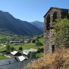 Vista del pueblo de Vall Ferrera con su campanario de piedra y montañas verdes al fondo.