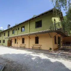 Edifici verd i groc amb taules de ping-pong i bancs a l'exterior. Un lloc ideal per a un refugi cap del rec.