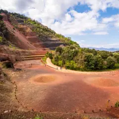 Paisaje volcánico en la Garrotxa con senderos y vegetación exuberante bajo un cielo azul con nubes.