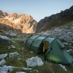 Tienda de campaña verde en un paisaje montañoso rocoso, ideal para acampada libre España.