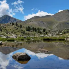 Reflejo de montañas y nubes en un lago sereno del valle de Madriu-Perafita-Claror.
