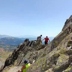 Trepando por rocas, un pic carlit con lagos turquesas de fondo.