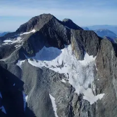Majestuoso pico perdiguero cubierto de nieve y roca, con un glaciar que desciende por sus laderas.