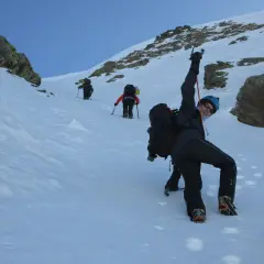 Un grupo de montañeros asciende por una ladera nevada. El pic de la serrera se alza imponente.