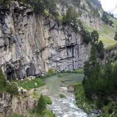 Impresionante pared rocosa junto a un río y vegetación exuberante en el forau de Aigualluts.