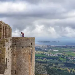Pareja contemplando el paisaje desde el **chateau de Montgri**, con el mar y la costa al fondo.