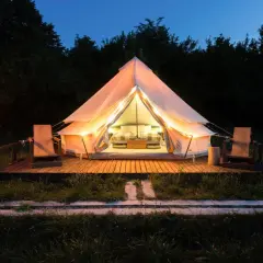 Tienda iluminada para camping Portugal, ideal para familias con niños. Dos sillas de madera esperan en la terraza.