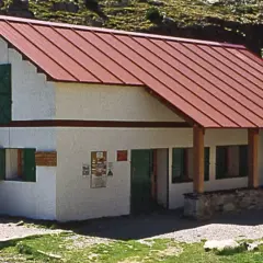 Un refugio de montaña en Cataluña, con tejado rojo y escaleras de piedra.