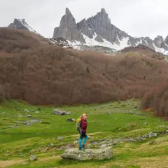 Senderista admira el majestuoso valle de Aspe, con picos nevados y bosques otoñales.
