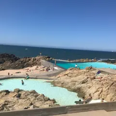 Piscinas naturais na praia de Matosinhos, Porto, com pessoas a nadar e a apanhar sol.