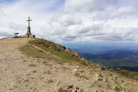 Cima de montaña con cruz y banco, ideal para **rutes per osona**. Paisaje de valles y nubes.