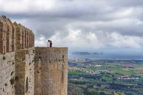 Pareja contemplando el paisaje desde el **chateau de Montgri**, con el mar y la costa al fondo.