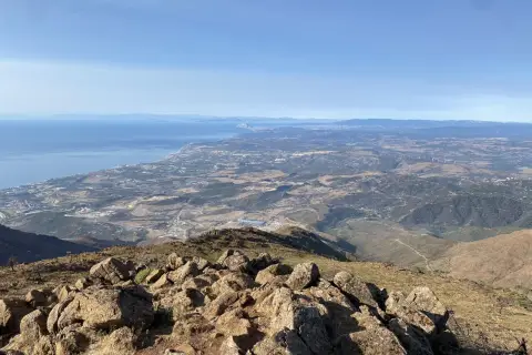 Vista panorámica desde la sierra bermeja, con el mar azul al fondo y un paisaje árido y rocoso en primer plano.