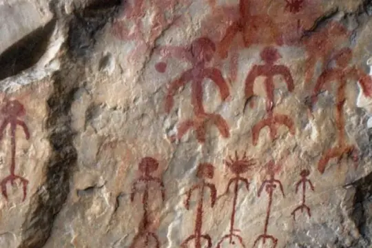 Antiguas pinturas rupestres rojas sobre roca, representando figuras humanas estilizadas y un sol.