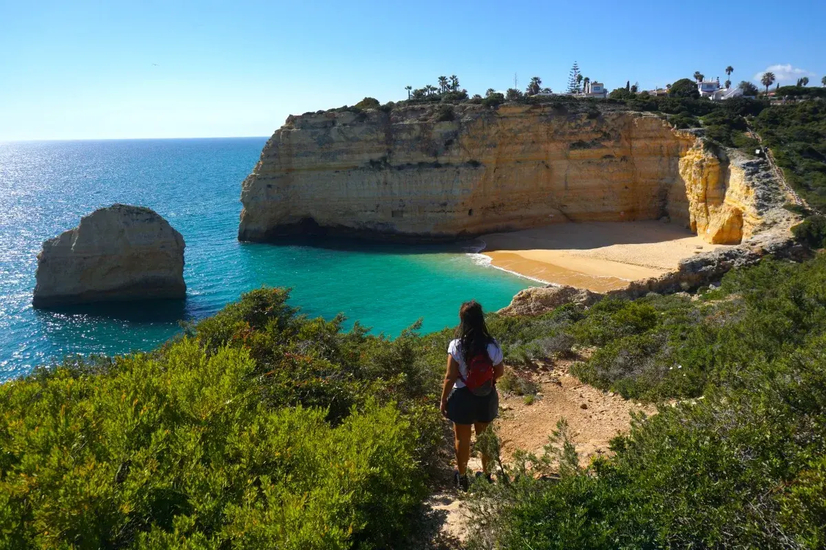 Una mujer admira las impresionantes calas del Algarve, con sus acantilados dorados y aguas turquesas.