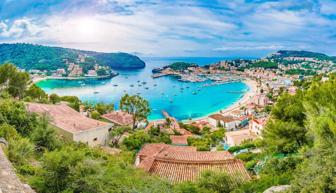 Bahía turquesa con barcos y casas en laderas verdes, un paraíso que evoca **islas secretas** y tranquilidad.