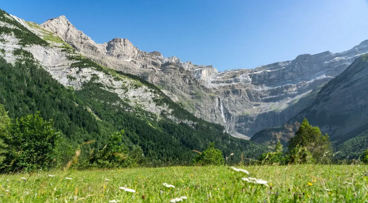 Majestuoso circo de Gavarnie con cascada y prado verde.