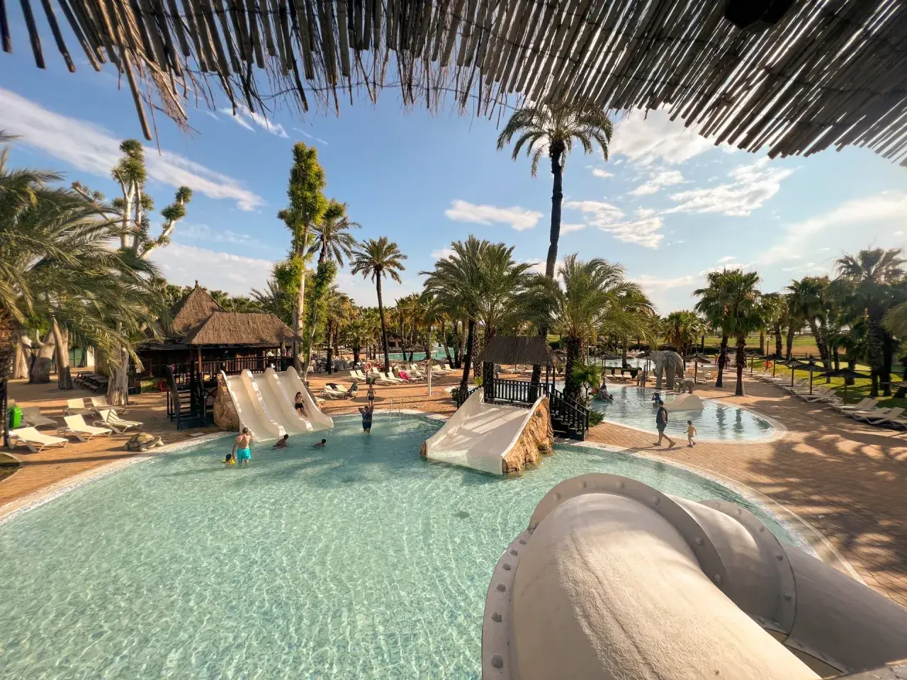 Disfruta de un día soleado en un camping con toboganes en España. Niños y adultos se divierten en la piscina y en los toboganes.