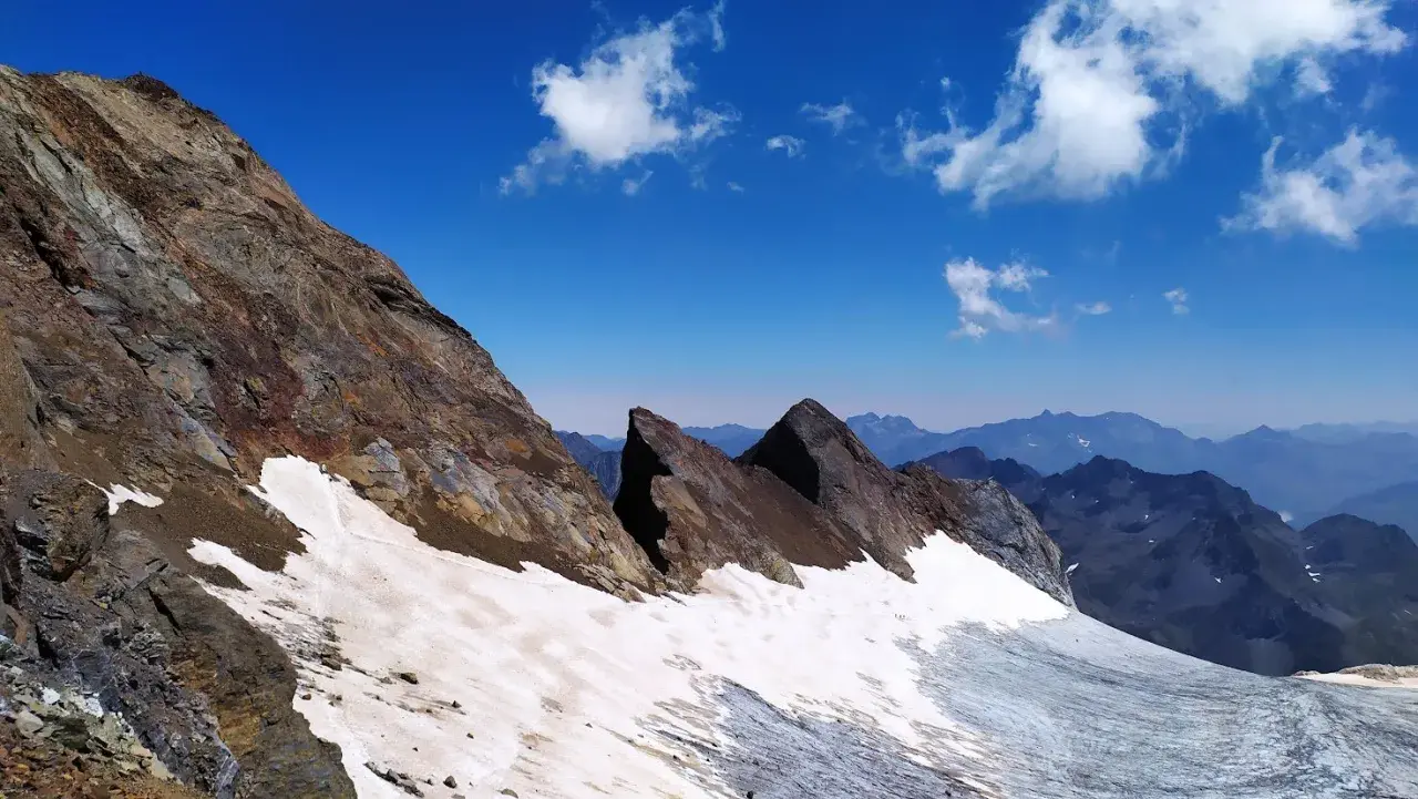 Paisaje de alta montaña con nieve y rocas en el pico Viñamala. El cielo azul intenso contrasta con las cumbres nevadas y las formaciones rocosas.