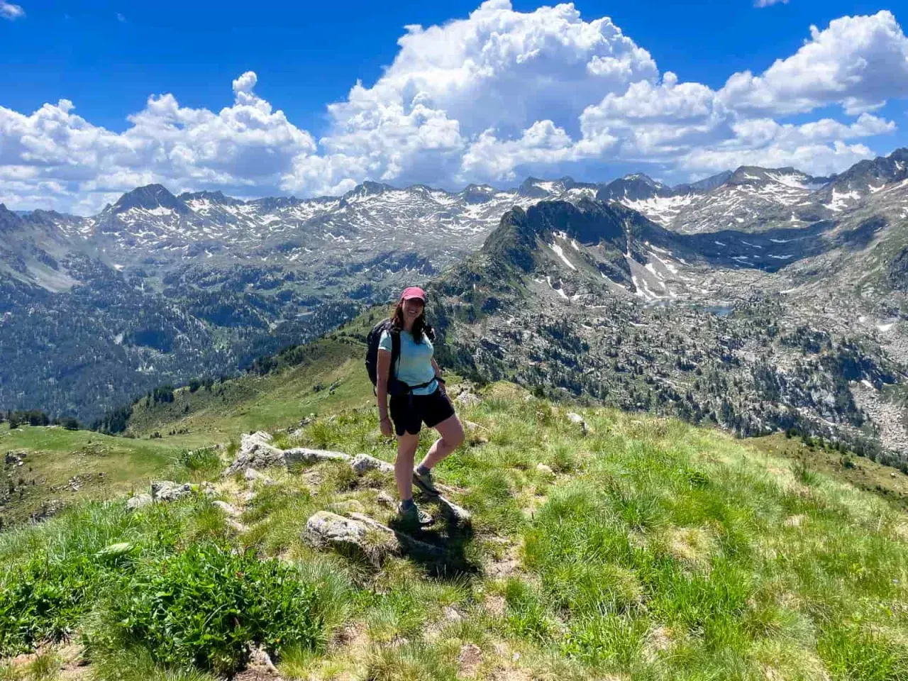 Senderista disfruta de las impresionantes vistas de las rutas del Valle de Arán, con picos nevados y un cielo azul con nubes.