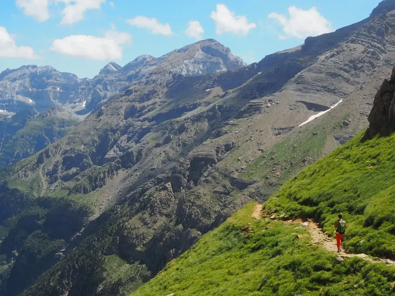 Senderista en un camino escarpado con vistas a las majestuosas montañas de Ordesa Monte Perdido.