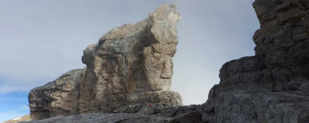 Impresionante vista de la brecha de Rolando, con imponentes formaciones rocosas y un cielo brumoso. Pequeños puntos de color sugieren la presencia de excursionistas.
