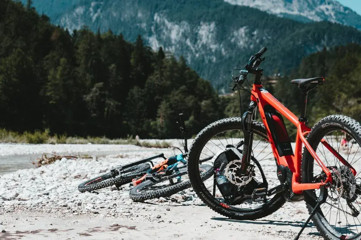Aventura en Croacia en bicicleta, con bicicletas de montaña listas junto a un río pedregoso y un bosque frondoso.